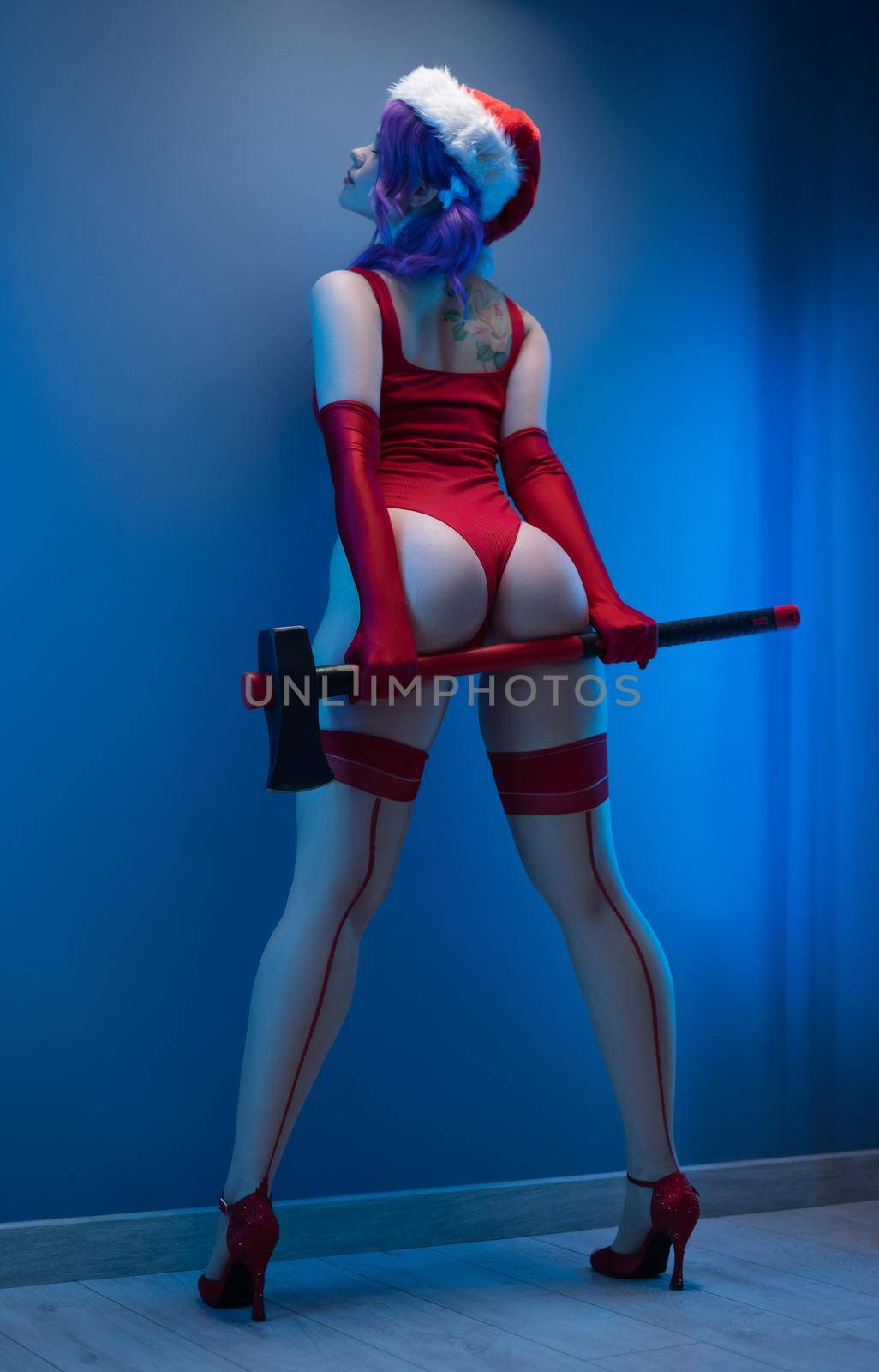 the sexy girl in red underwear and santa hat with an axe on a blue background