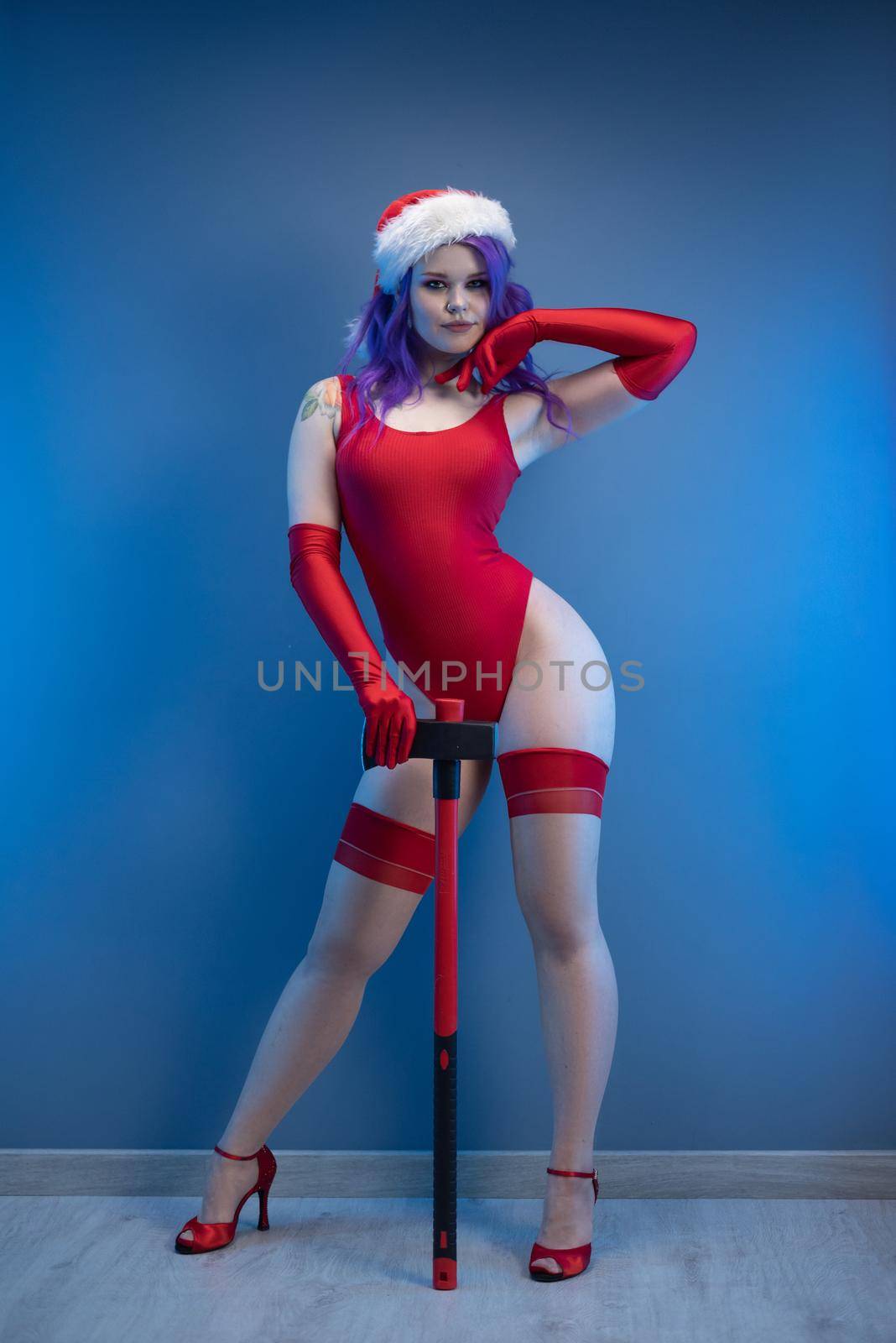 the sexy girl in red underwear and santa hat with an axe on a blue background