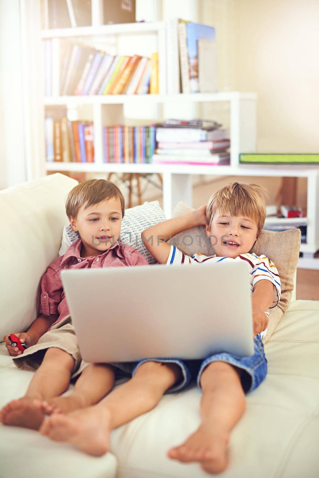 Learning about technology during playtime. two little boys using a laptop together. by YuriArcurs