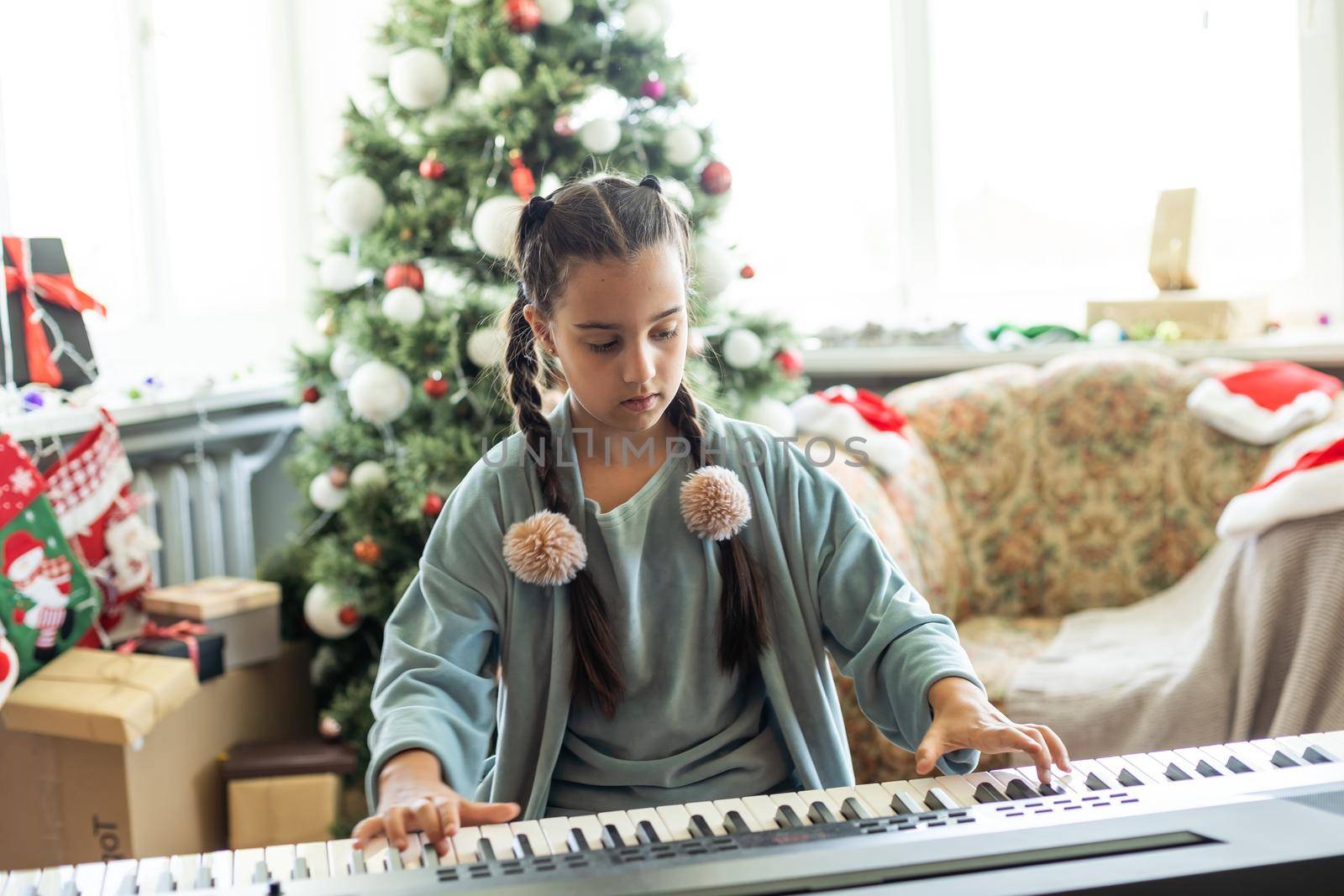 Christmas child little girl playing on piano at home.