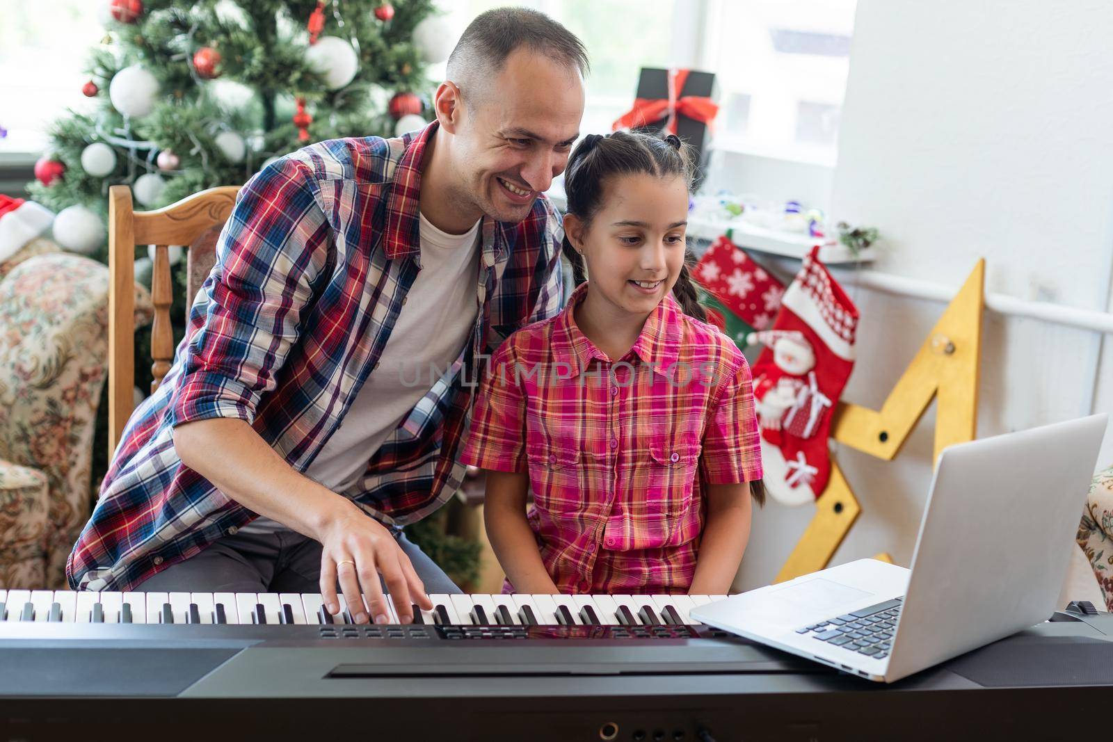 father and daughter playing the piano at christmas.