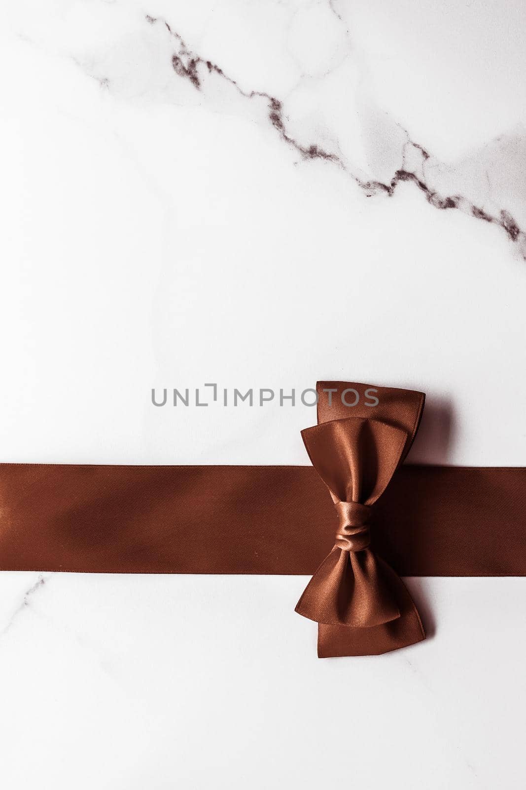 Chocolate brown silk ribbon on marble background, flatlay by Anneleven