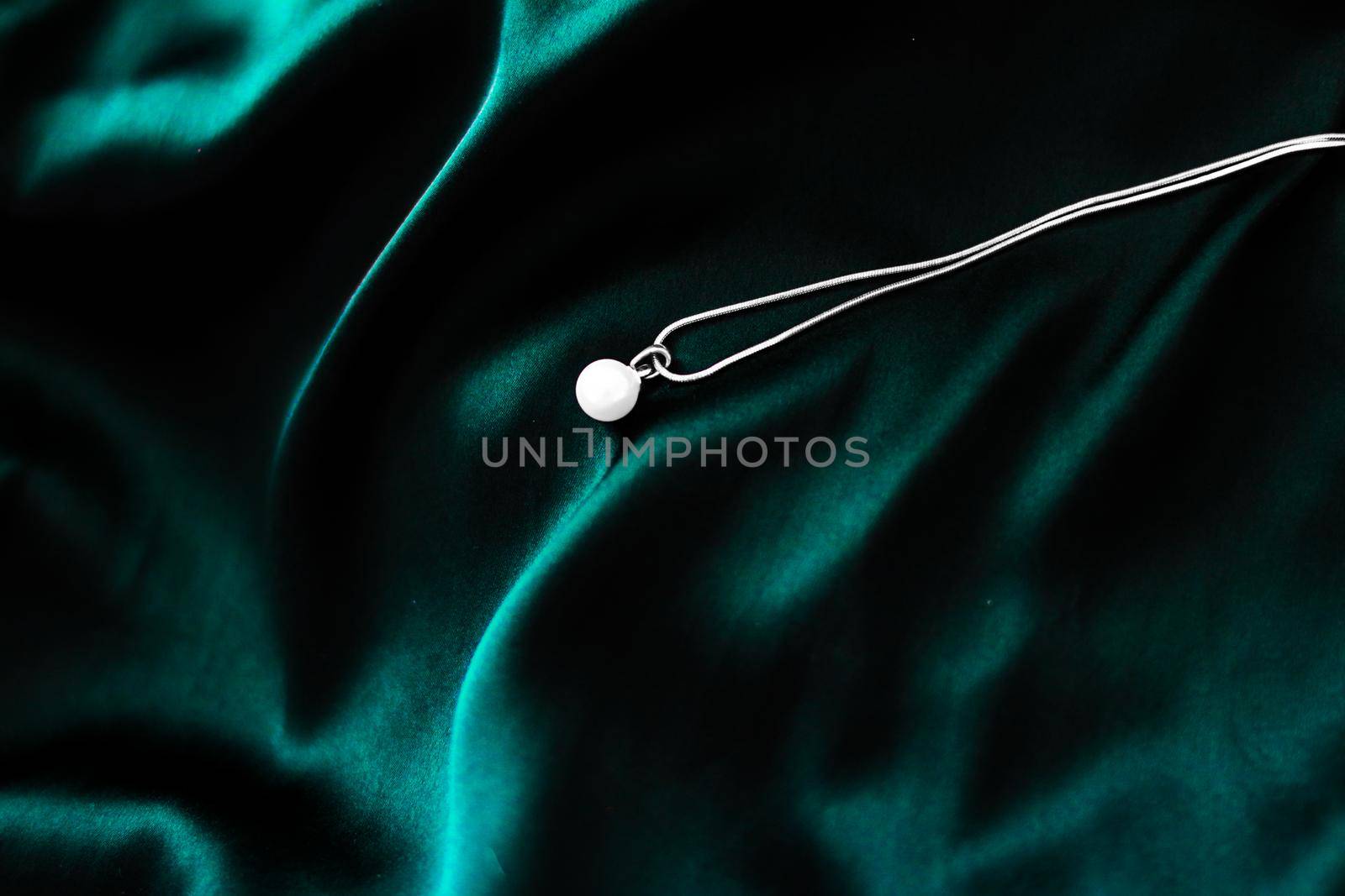 Luxury white gold pearl necklace on dark emerald green silk background, holiday glamour jewelery present by Anneleven