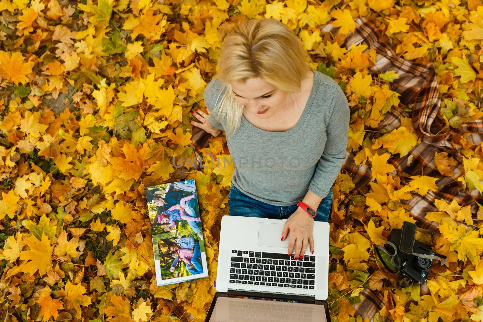 woman with laptop and photo book in autumn park by Andelov13