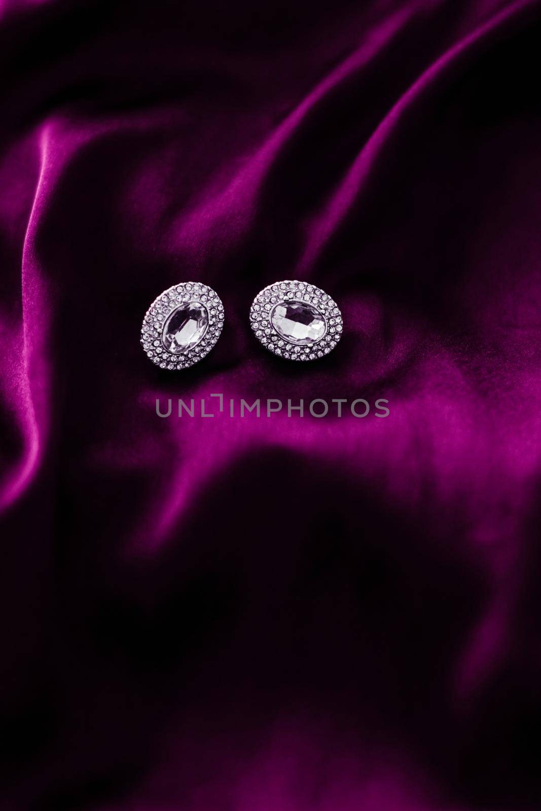 Luxury diamond earrings on dark pink silk fabric, holiday glamour jewelery present by Anneleven
