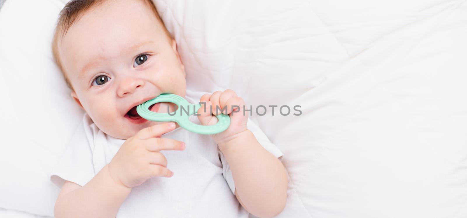 A baby with a teether on a white background . Teething. Children's article. Copy space