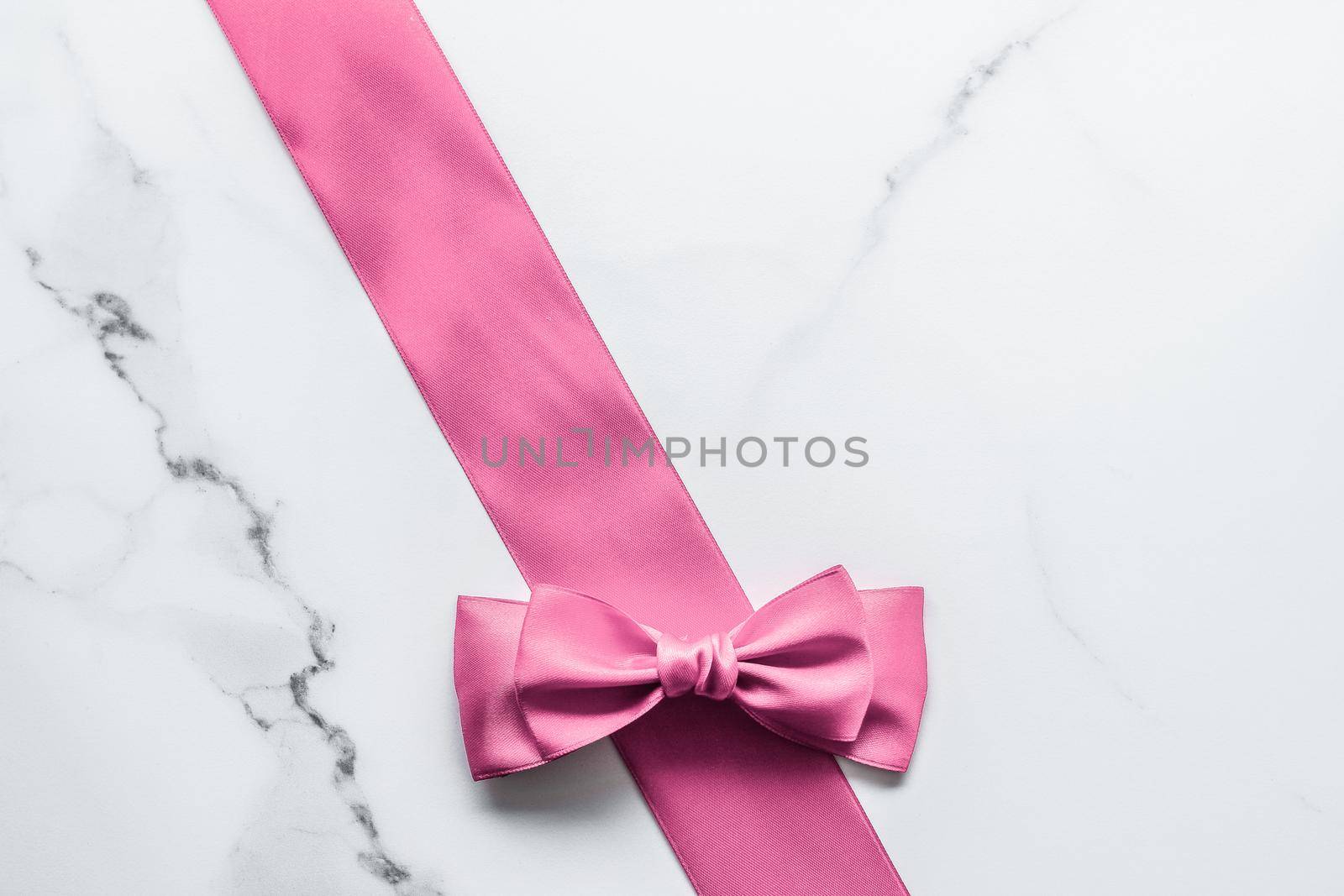 Pink silk ribbon and bow on marble background, girl baby shower present and glamour fashion gift decor for luxury beauty brand, holiday flatlay design by Anneleven