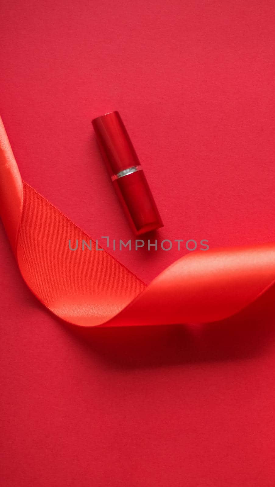 Luxury lipstick and silk ribbon on red holiday background, make-up and cosmetics flatlay for beauty brand product design by Anneleven