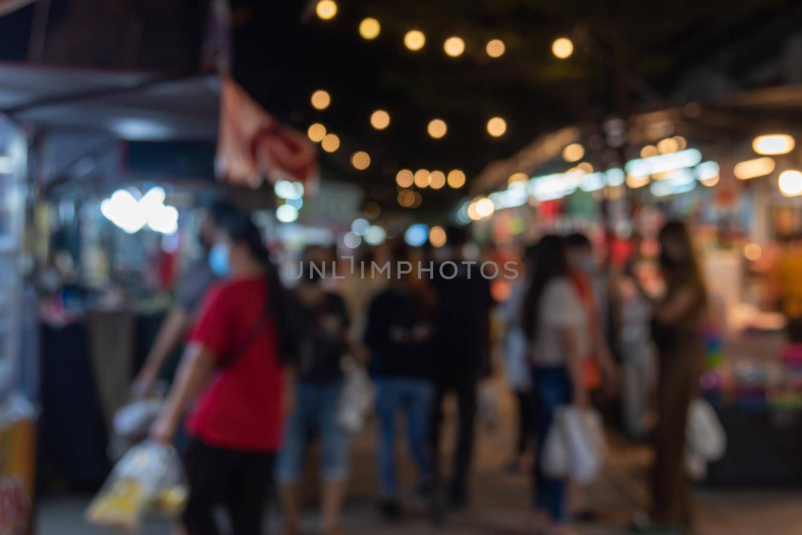 blurred image of night market festival people walking on road with light bokeh for background. by aoo3771