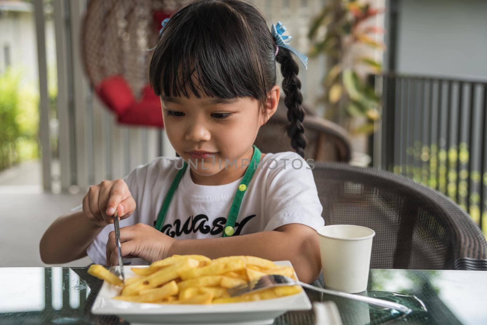 Young Asian girl eating french fries young kid fun happy potato fast food.