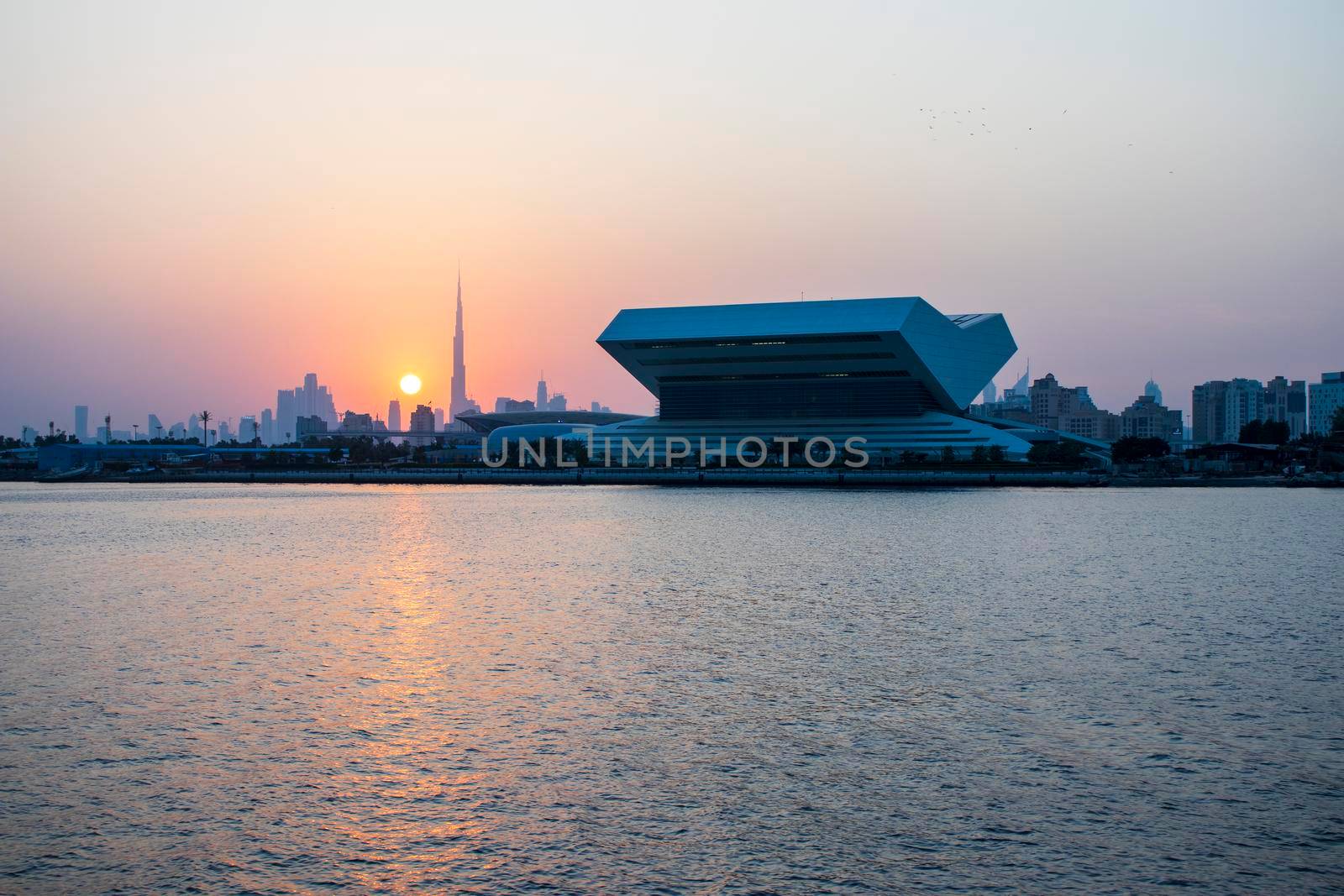 Sunset at Dubai Festival city. New building of Sheikh Muhammad Bin Rashid library on the scene as well as tallest building in the world Burj Khalifa on background. Outdoors