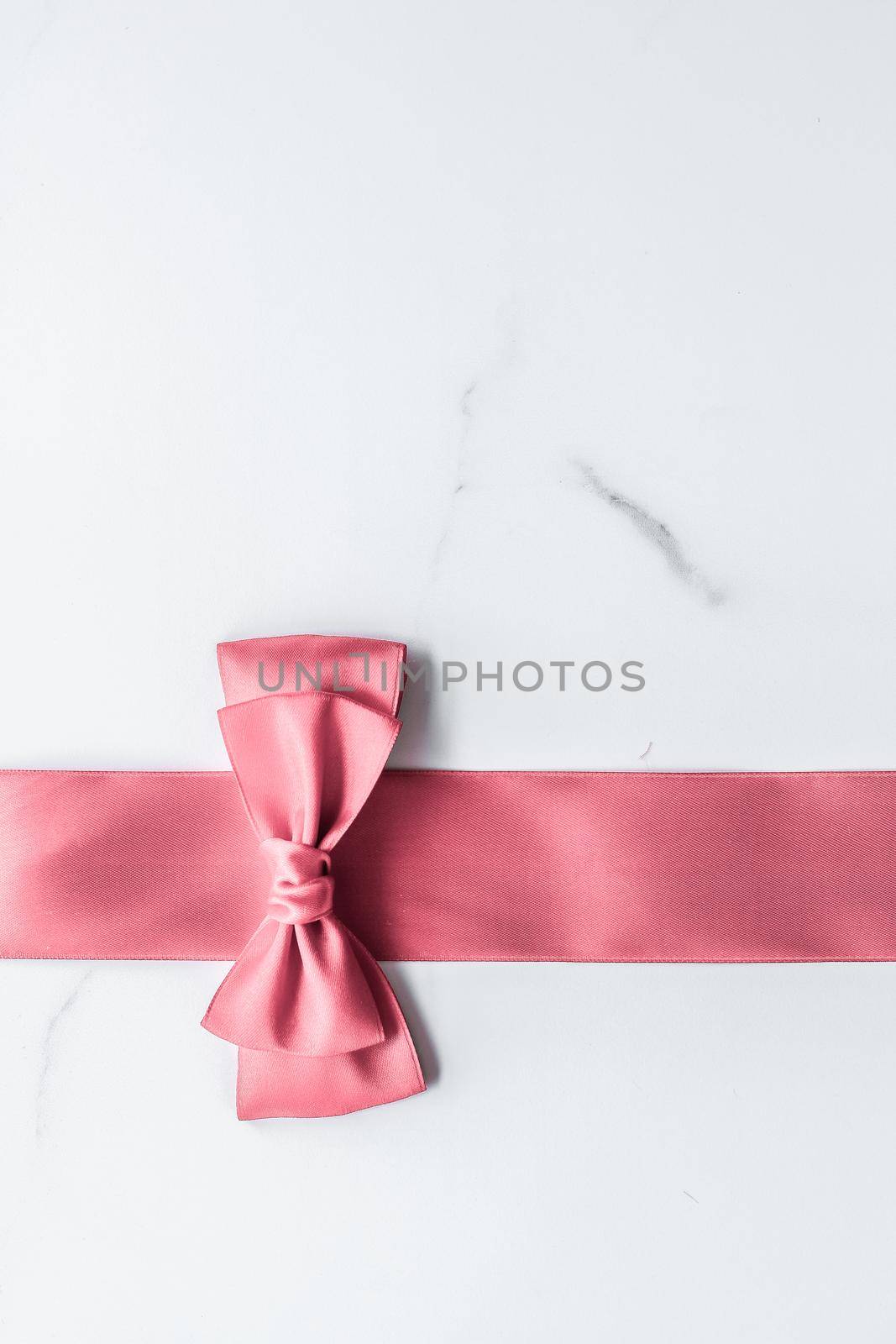 Coral silk ribbon and bow on marble background, girl baby shower present and glamour fashion gift decor for luxury beauty brand, holiday flatlay design by Anneleven