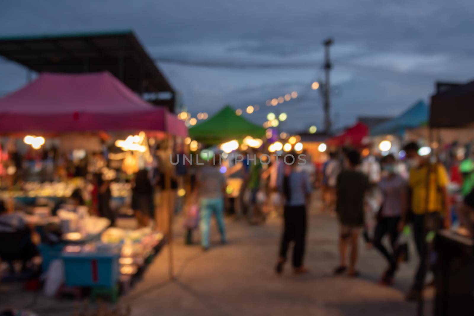 blurred image of night market festival people walking on road with light bokeh for background. by aoo3771