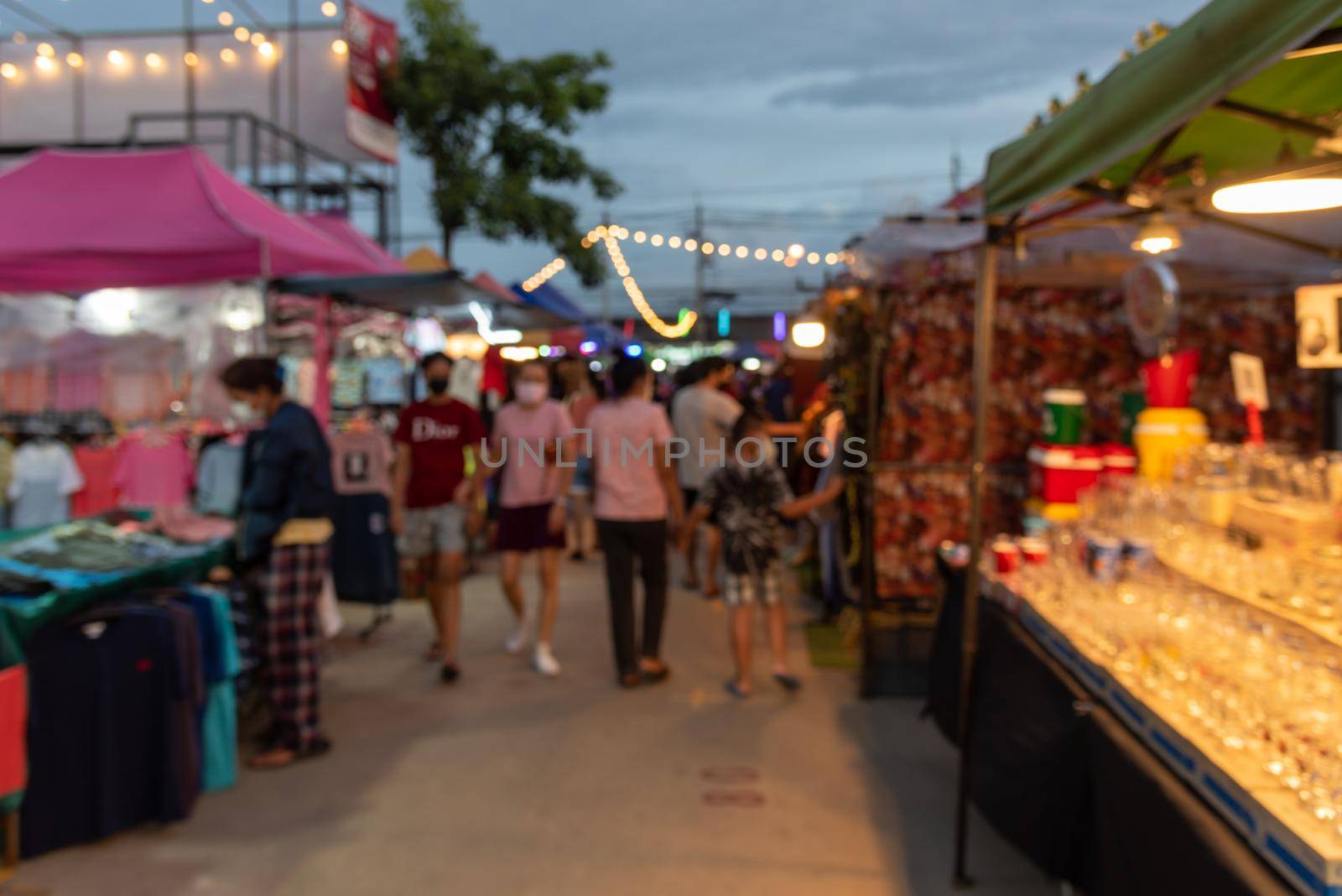 blurred image of night market festival people walking on road with light bokeh for background.
