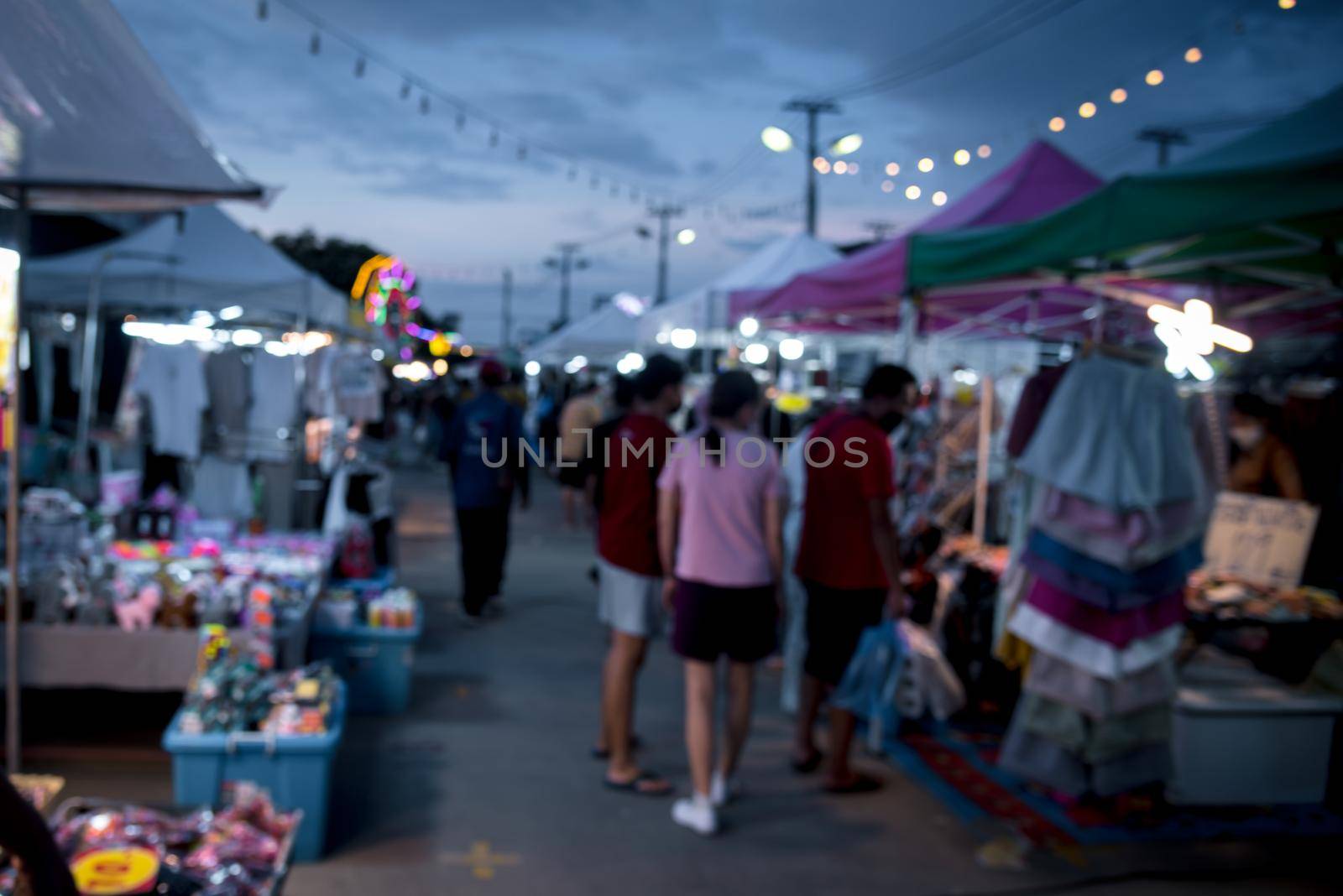blurred image of night market festival people walking on road with light bokeh for background. by aoo3771