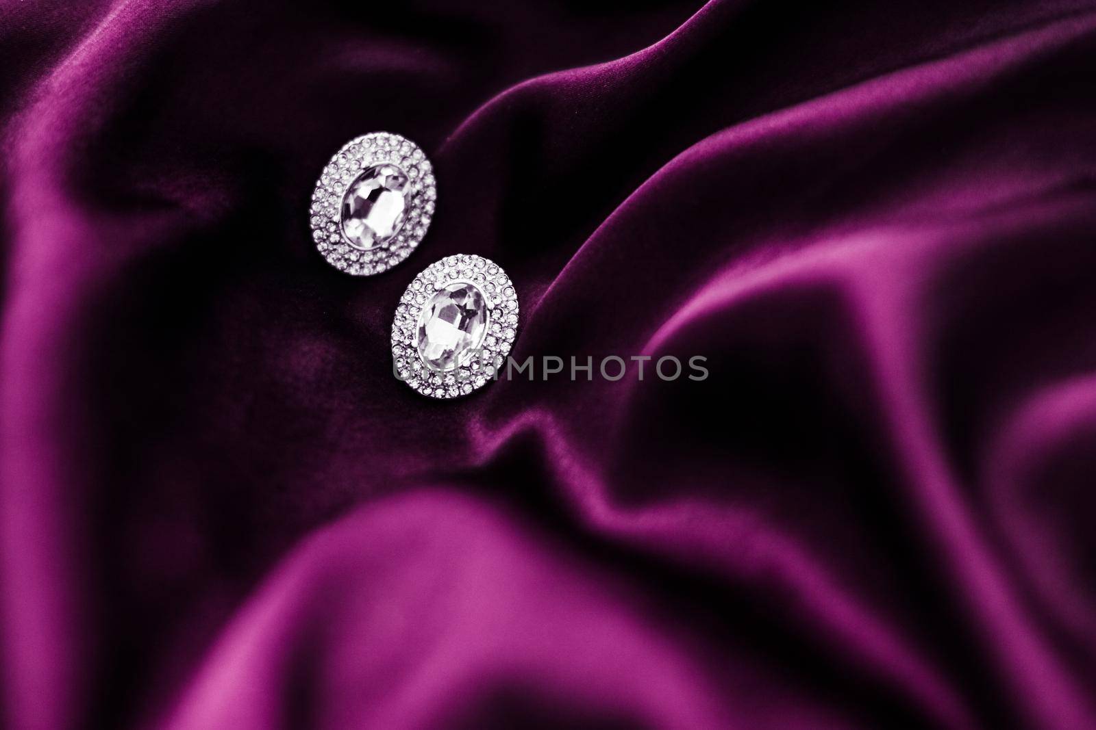 Jewellery brand, elegant fashion and bridal luxe gift concept - Luxury diamond earrings on dark pink silk fabric, holiday glamour jewelery present