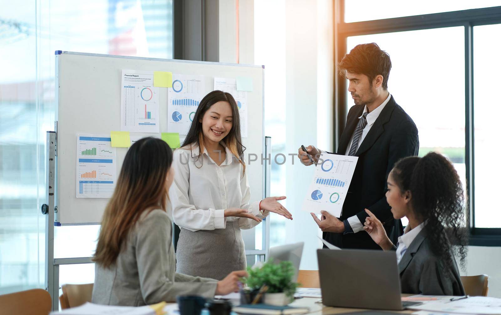 Group of young Asian business people stand talk, consult, discuss working with new startup project idea presentation analyze plan marketing and investment. by wichayada