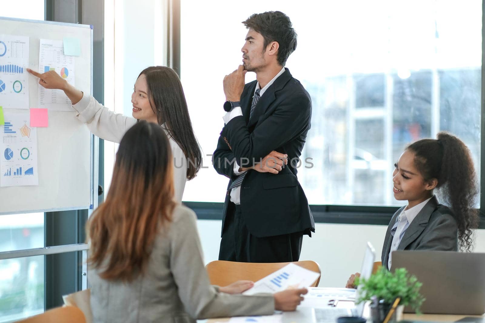 Female Operations Manager Holds Meeting Presentation for a Team of Economists. Asian Woman Uses Digital Whiteboard with Growth Analysis, Charts, Statistics and Data. People Work in Business Office. by wichayada