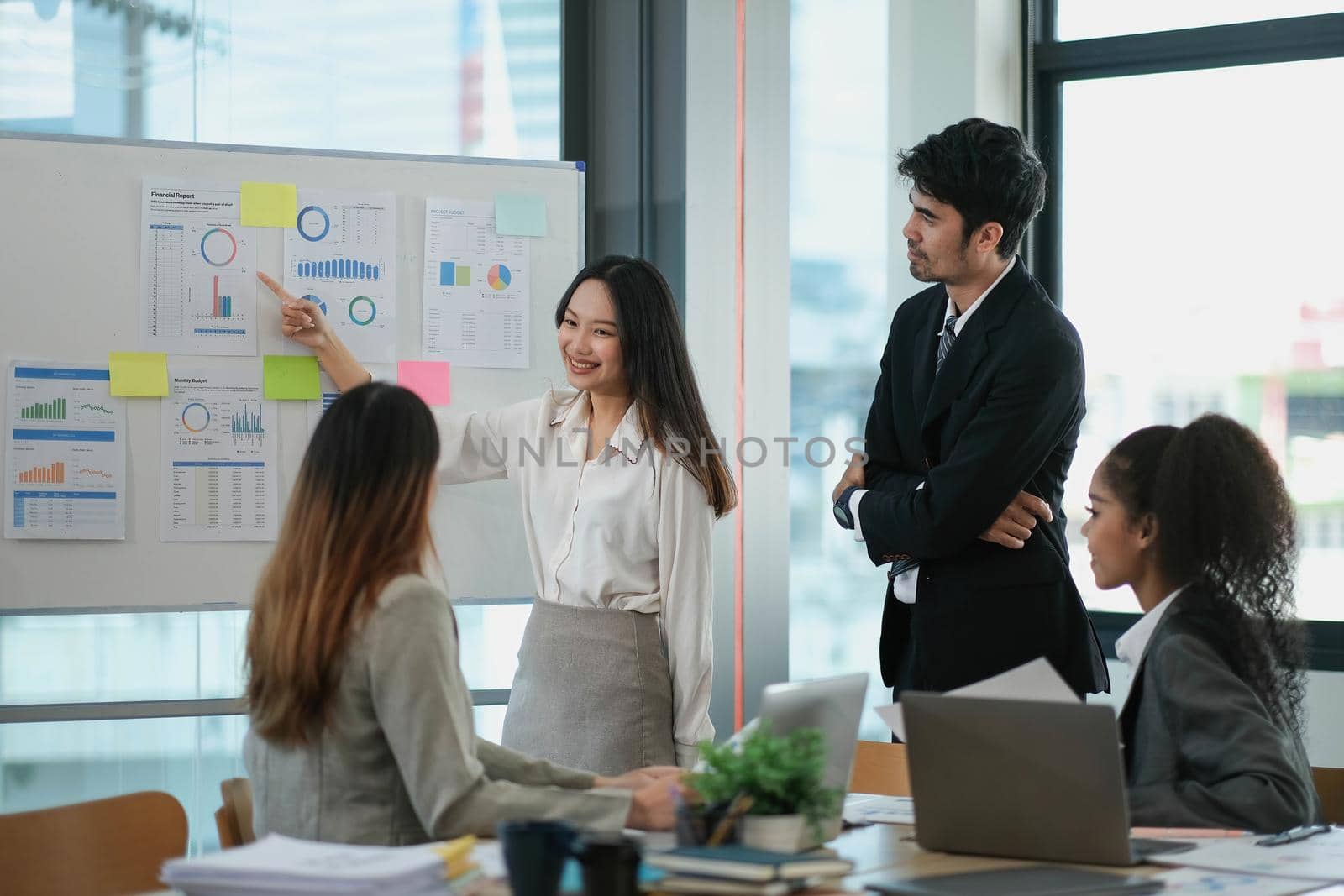Female Operations Manager Holds Meeting Presentation for a Team of Economists. Asian Woman Uses Digital Whiteboard with Growth Analysis, Charts, Statistics and Data. People Work in Business Office. by wichayada