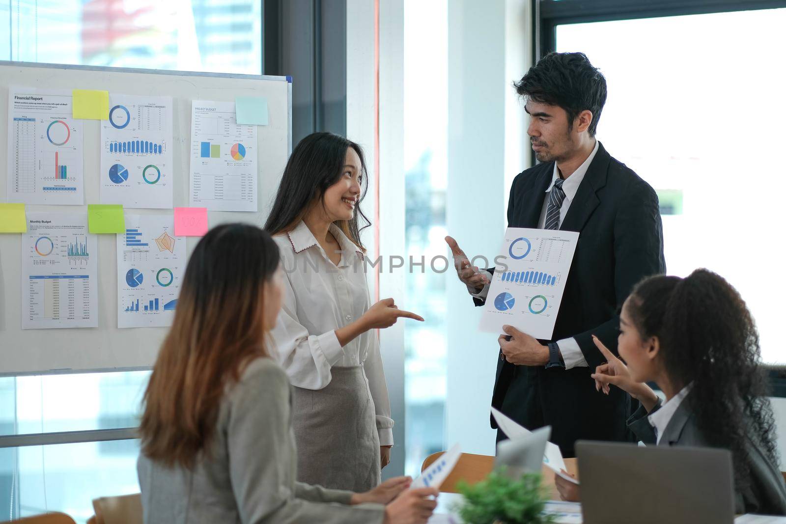 Group of young Asian business people stand talk, consult, discuss working with new startup project idea presentation analyze plan marketing and investment..