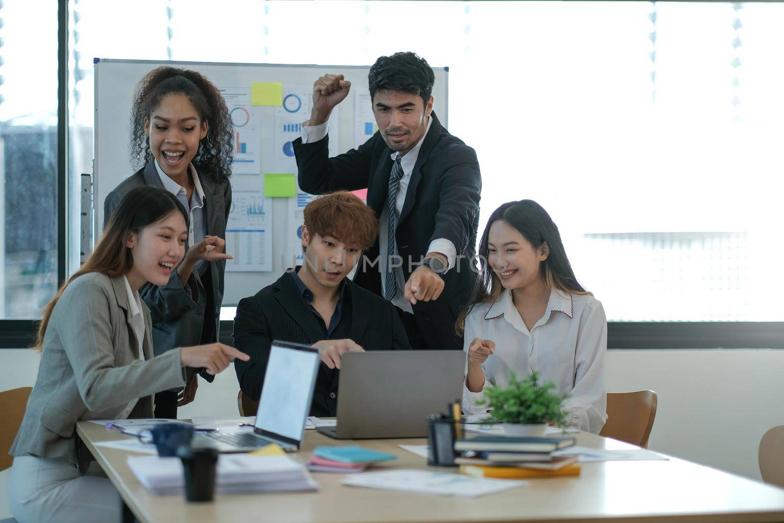Young happy Asian business man, woman work together, celebrate success in start up office. Creative team brainstorm meeting, businesspeople colleague partnership or office coworker teamwork concept.