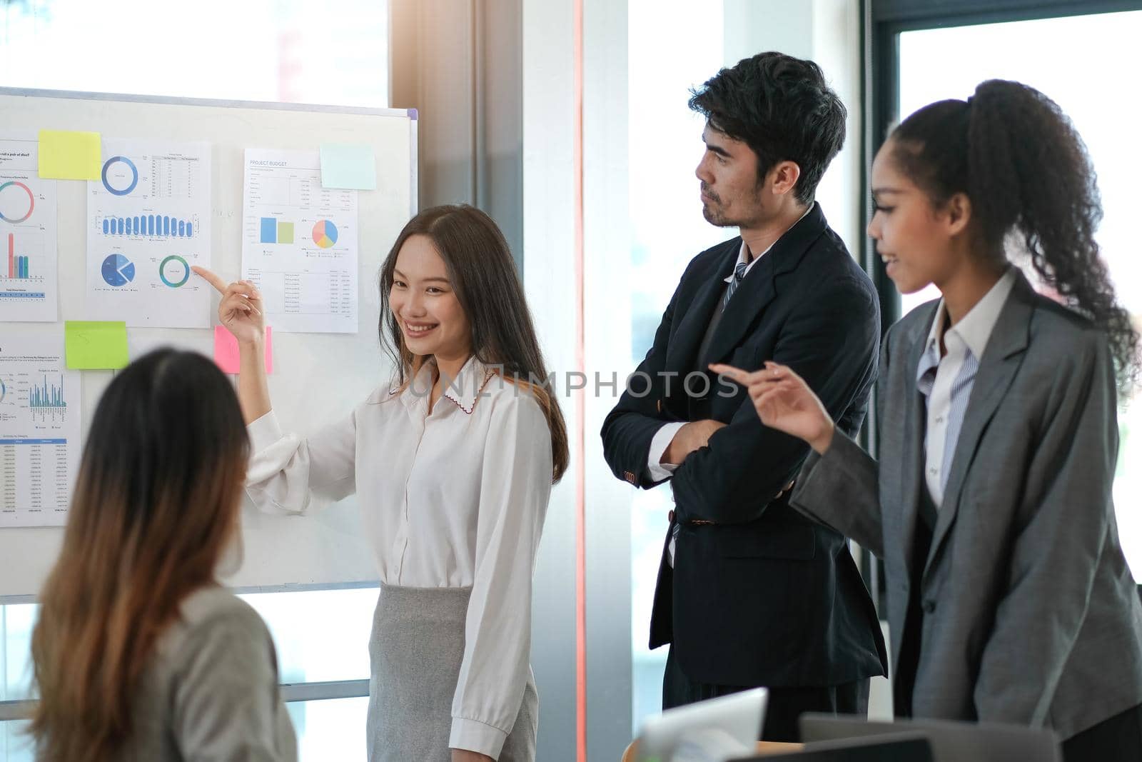 Female Operations Manager Holds Meeting Presentation for a Team of Economists. Asian Woman Uses Digital Whiteboard with Growth Analysis, Charts, Statistics and Data. People Work in Business Office. by wichayada