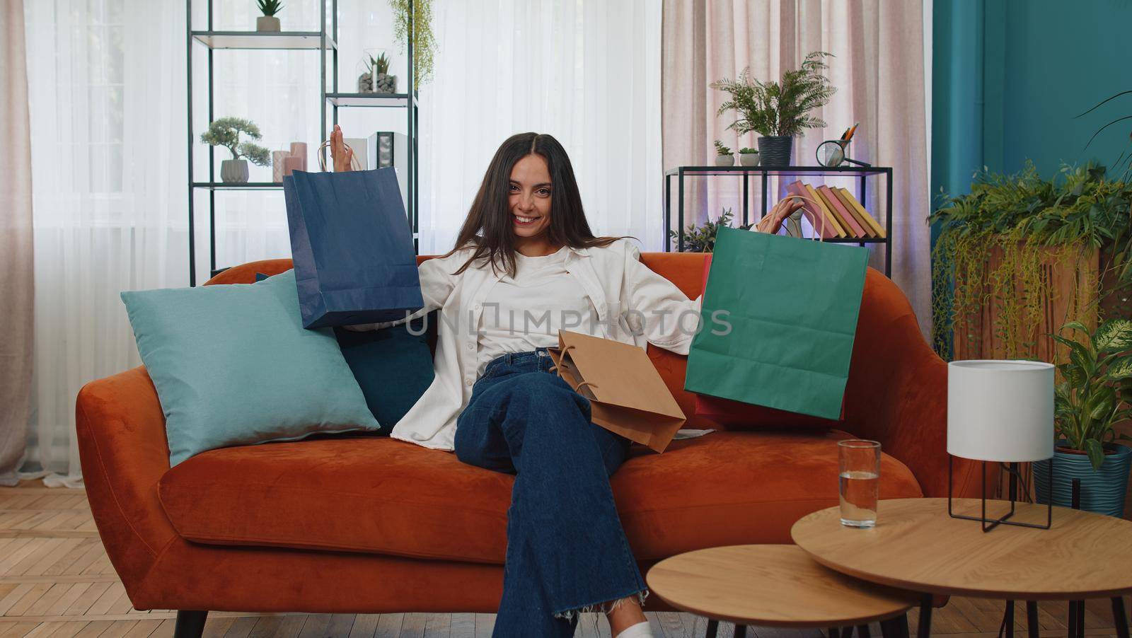 Portrait of caucasian adult girl happy shopaholic consumer came back home after shopping sale with bags. Young woman satisfied received parcels from online order at modern home apartment living room