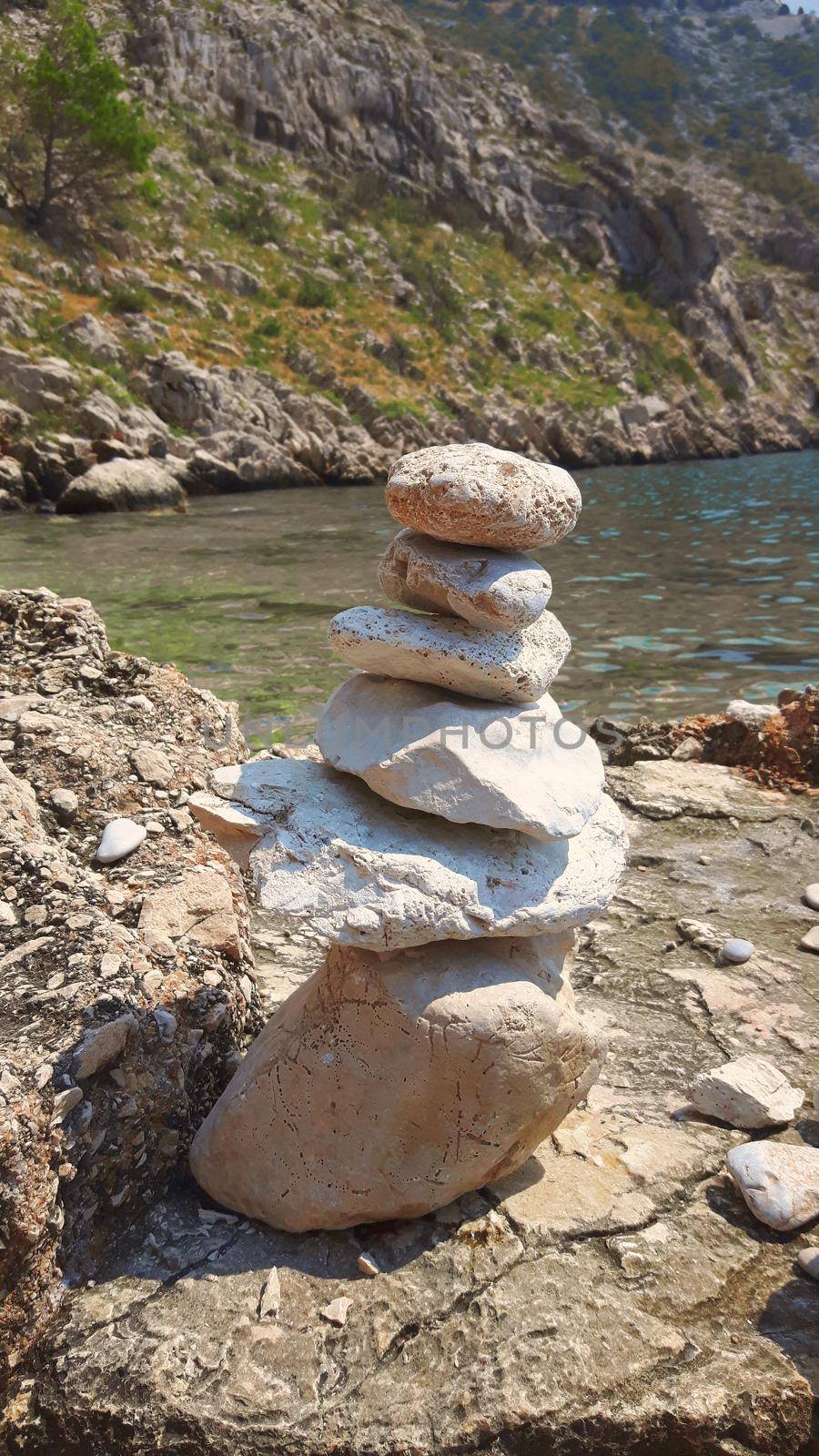 balanced Zen rocks art stacked in flowing water stream by banate