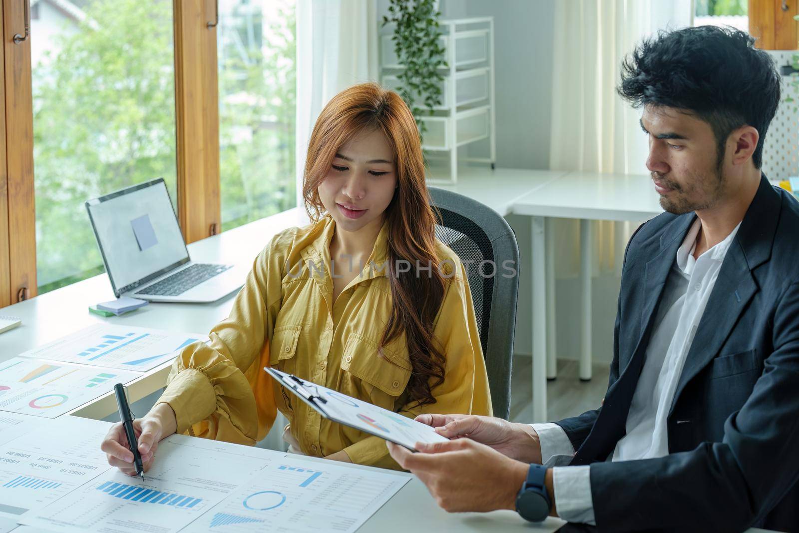 A portrait of a female business owner consulting a male salesperson to devise a strategy to increase revenue from new incoming goods using investment budget documents and an analytical computer.