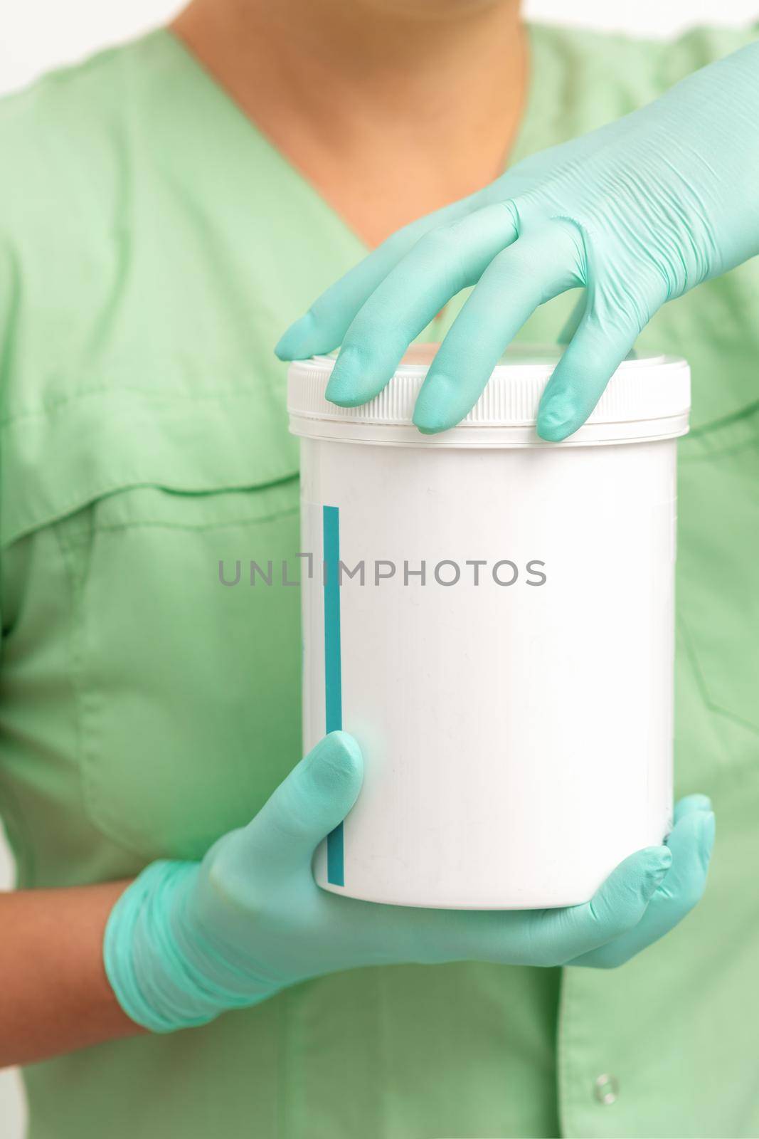 Hands in protective gloves of beautician open a white body cream jar on white background