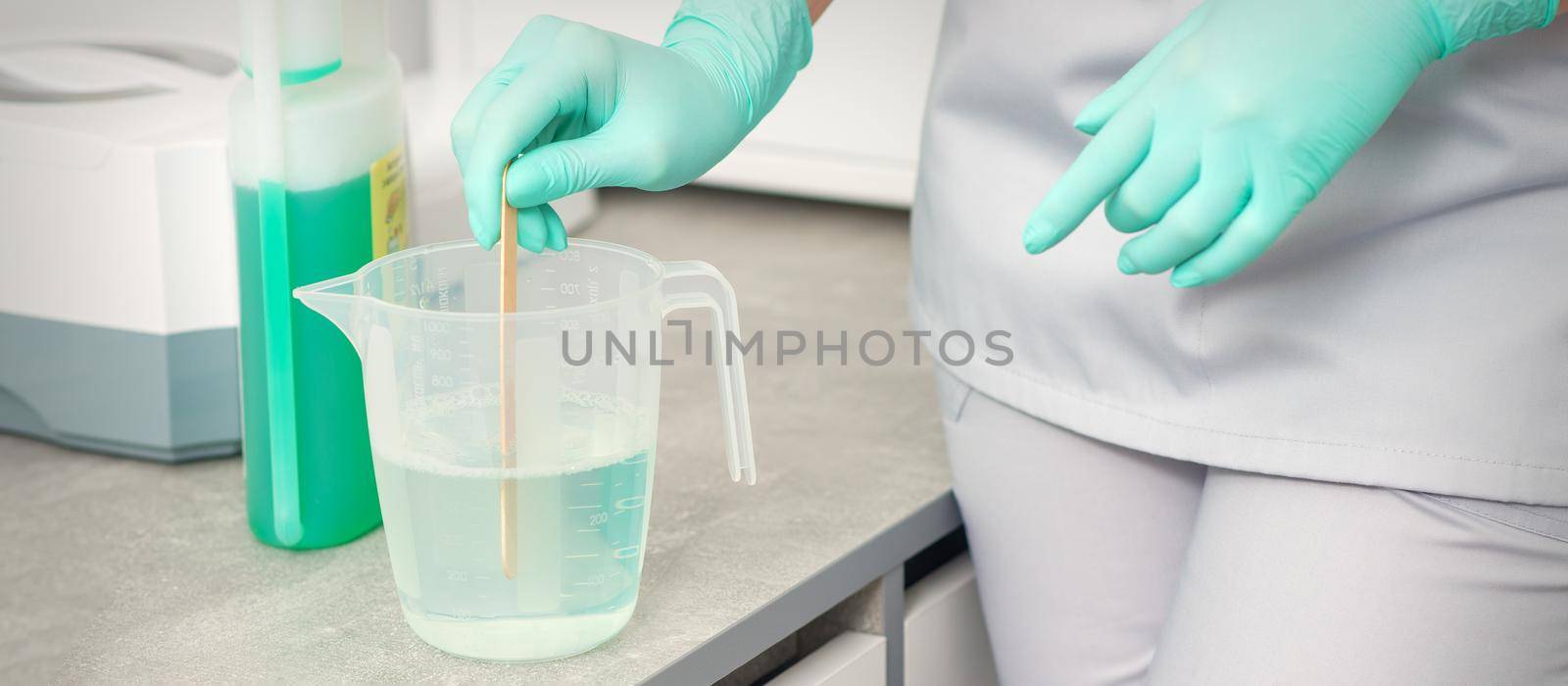 The beautician uses a stick to mix disinfectant into the water. Sterilization of tools