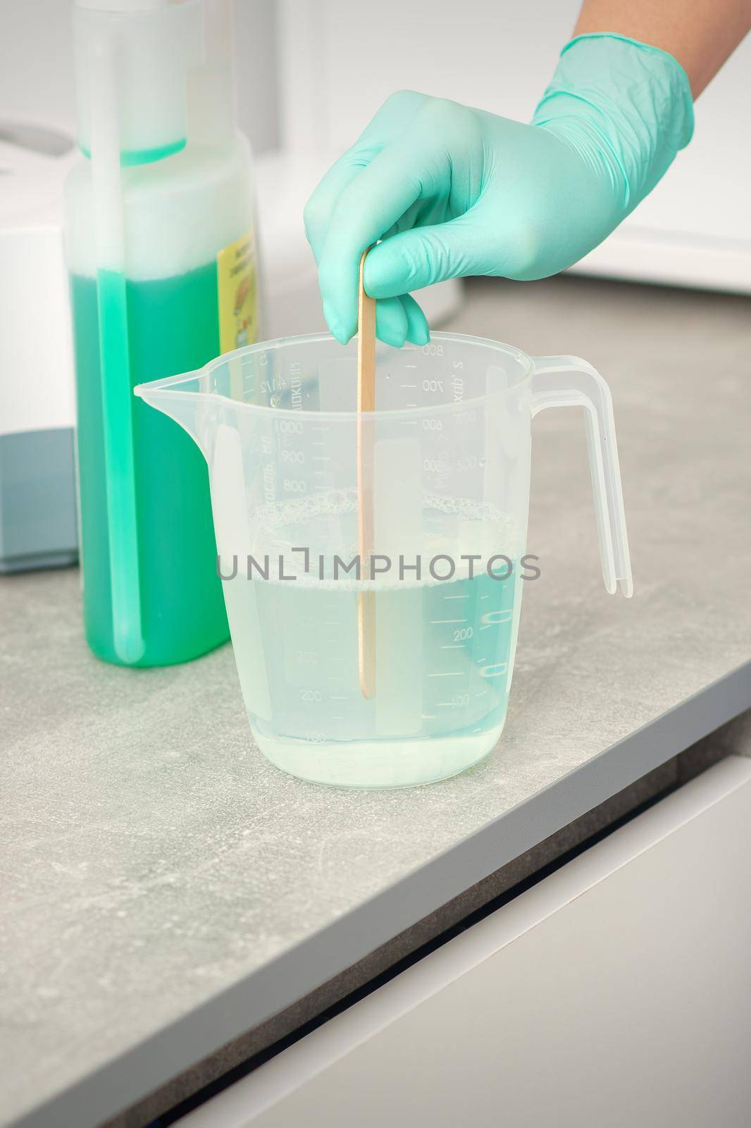 The beautician uses a stick to mix disinfectant into the water. Sterilization of tools