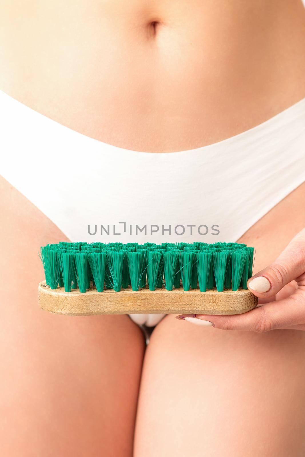 A woman in white panties holds a clothes brush on a white background. Depilation on the bikini zone. by okskukuruza