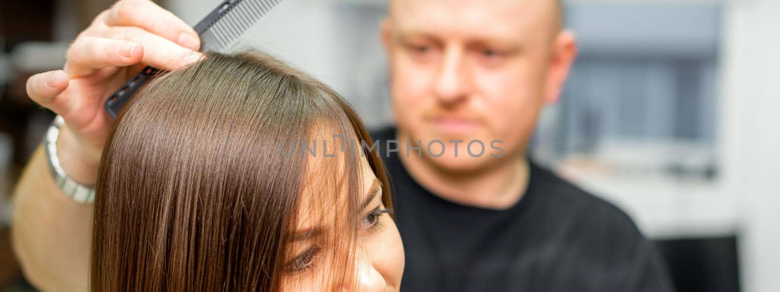Young caucasian brunette woman having her hairstyling by a male hairdresser at a parlor. by okskukuruza