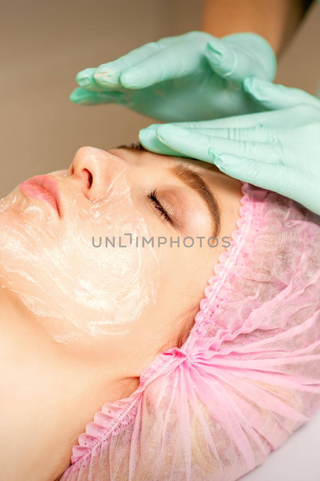 Face peeling at the beautician. Facial treatment. The beautician applies a cleansing face mask to the female patient