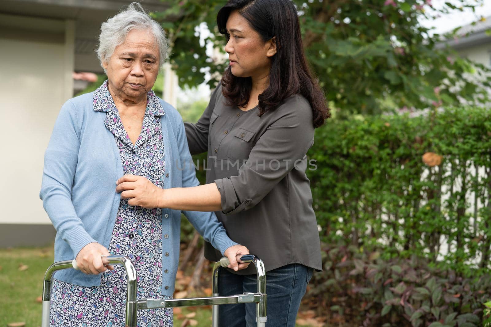 Caregiver help and care Asian senior or elderly old lady woman use walker with strong health while walking at park in happy fresh holiday.