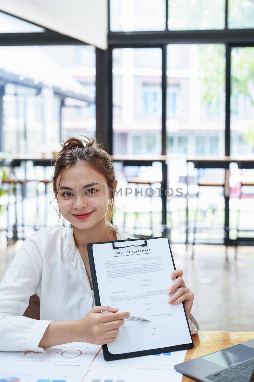 Portrait of a female business owner reading important documents before signing to verify approval of investment budget for their company.