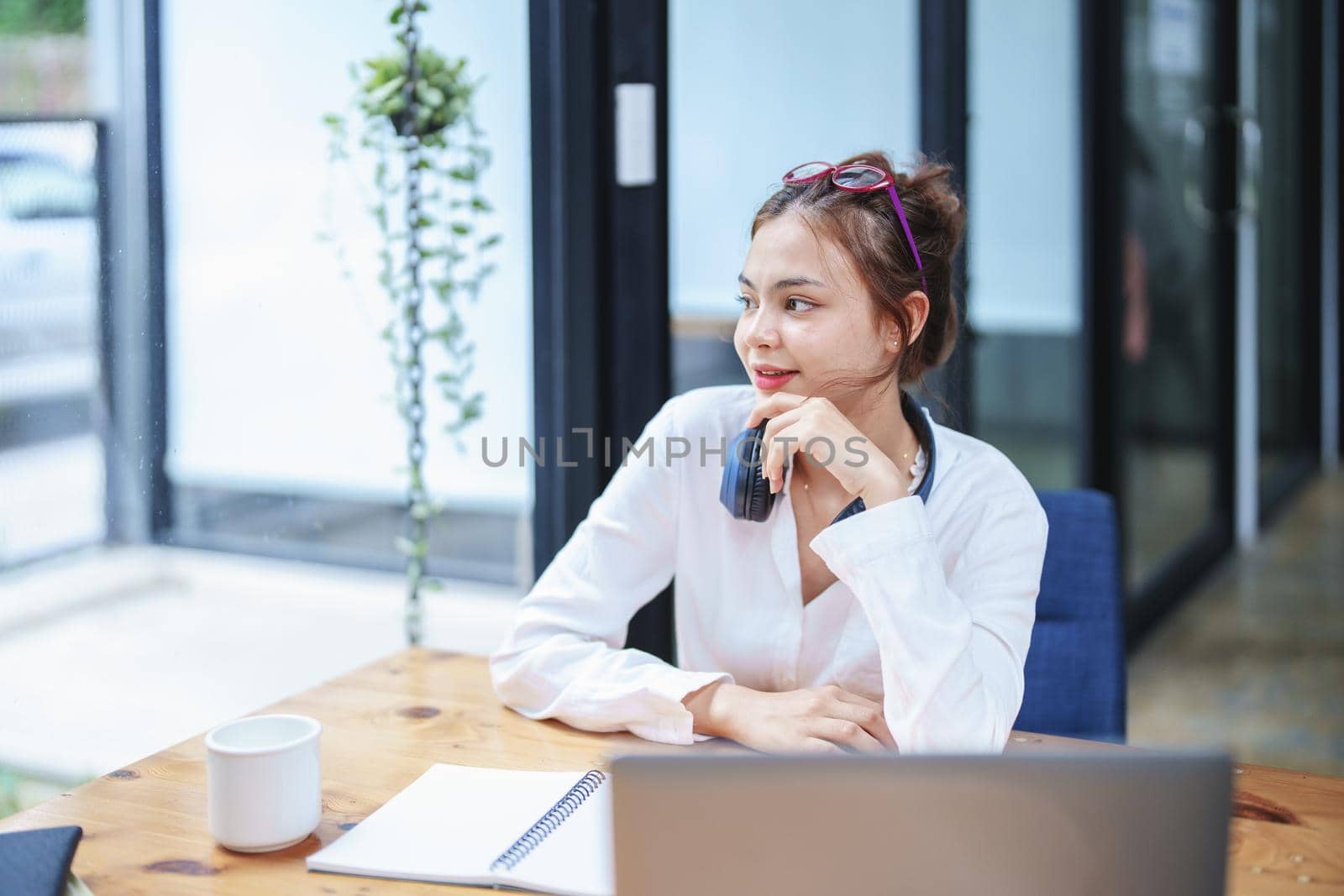 Portrait of a beautiful woman showing a smiling face and using a computer and notebook to work.