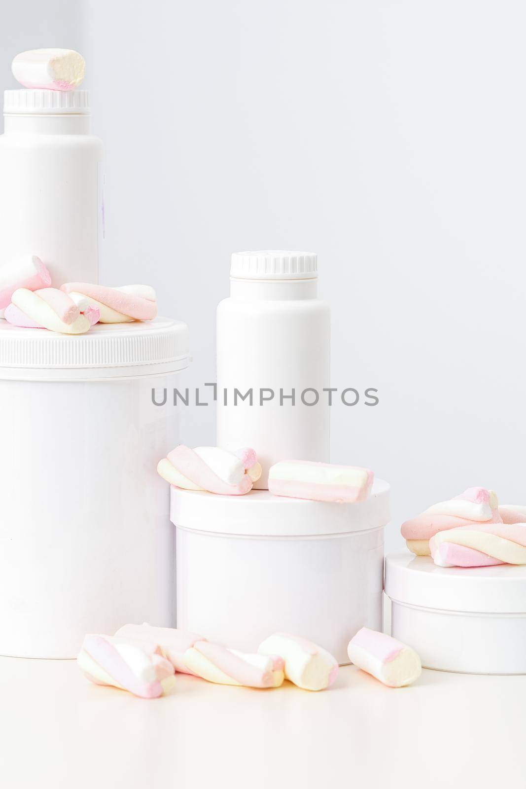 Cosmetic skincare packaging. Beauty product on white background. White jars with marshmallows on the white table. by okskukuruza