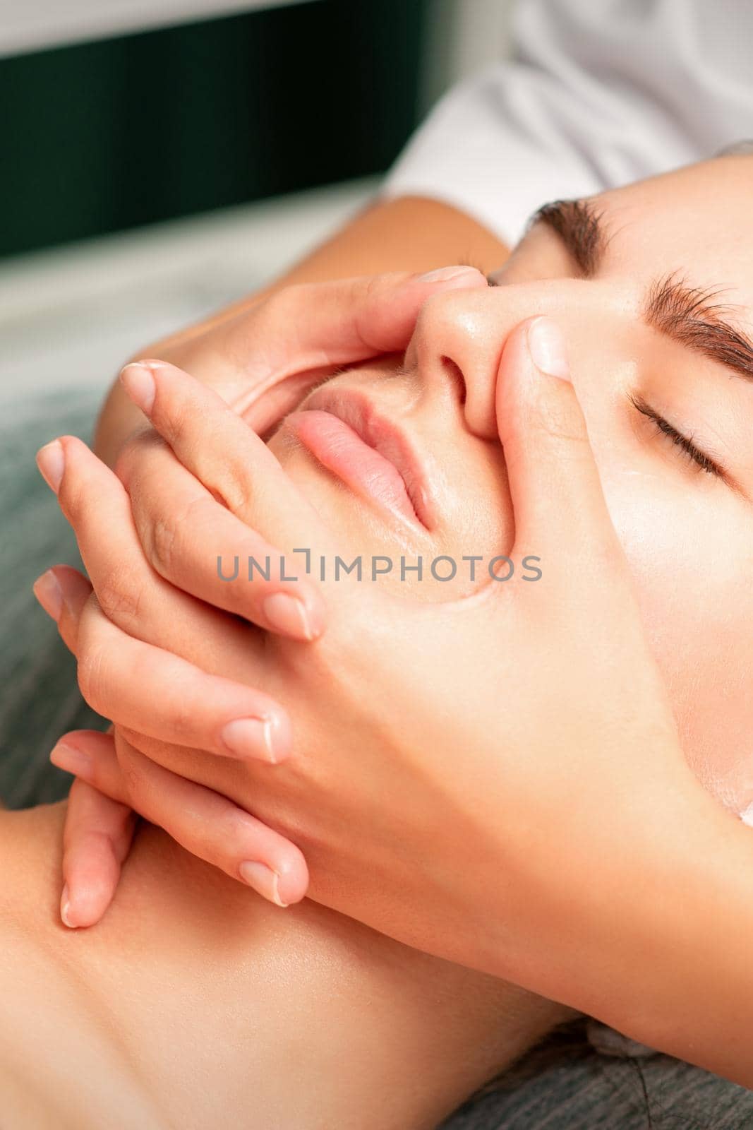 A young caucasian woman getting facial massage in a spa. by okskukuruza