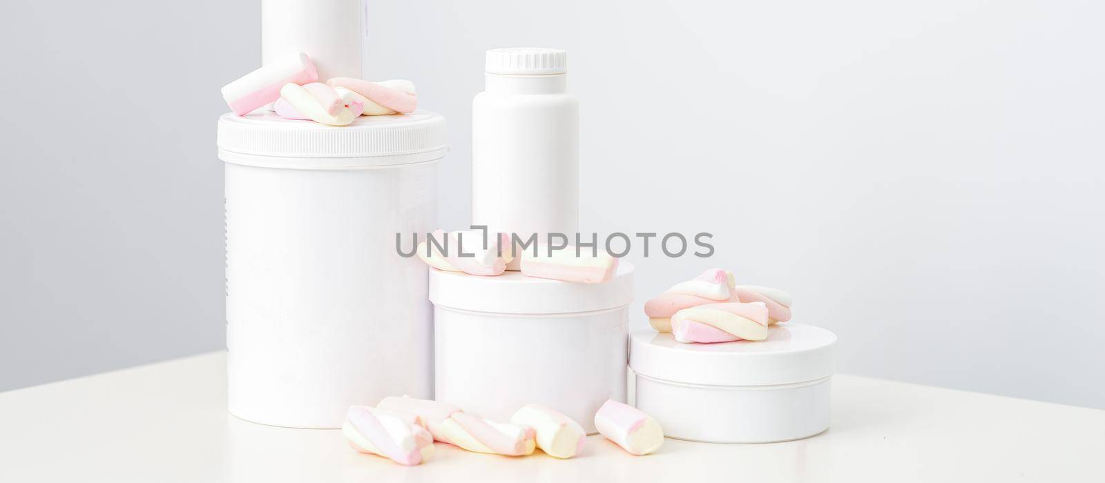 Cosmetic skincare packaging. Beauty product on white background. White jars with marshmallows on the white table. by okskukuruza