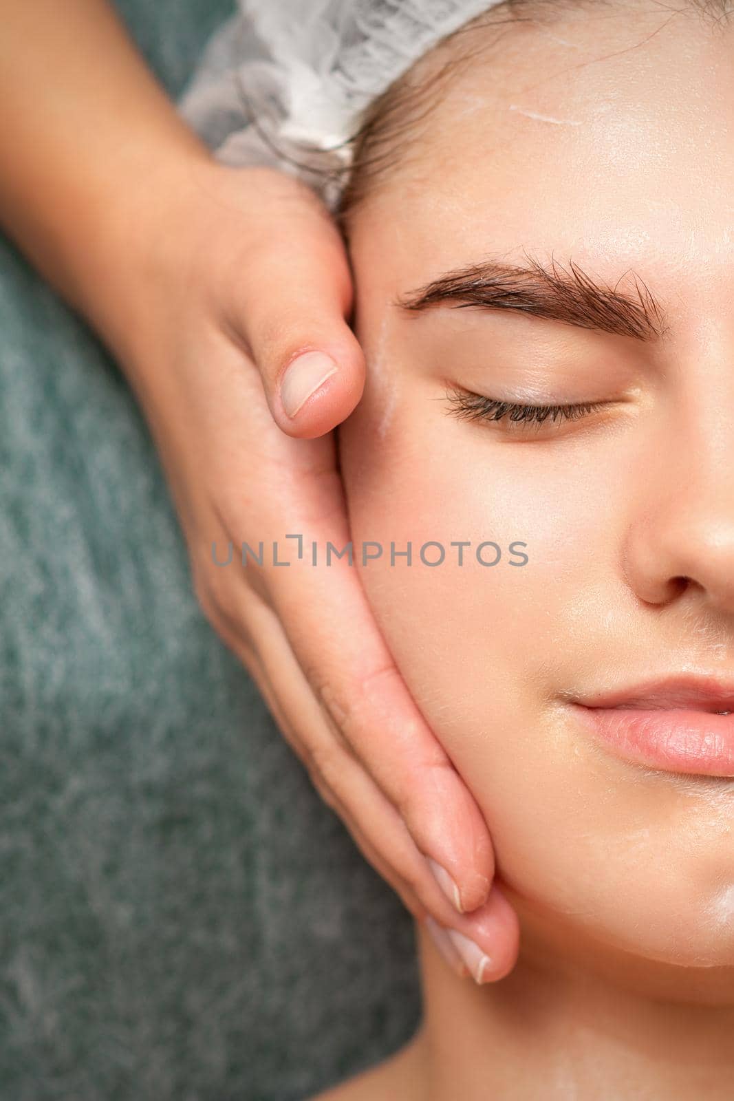 Spa facial skincare. Close-up of a young caucasian woman getting spa moisturizing face massage treatment at beauty spa salon