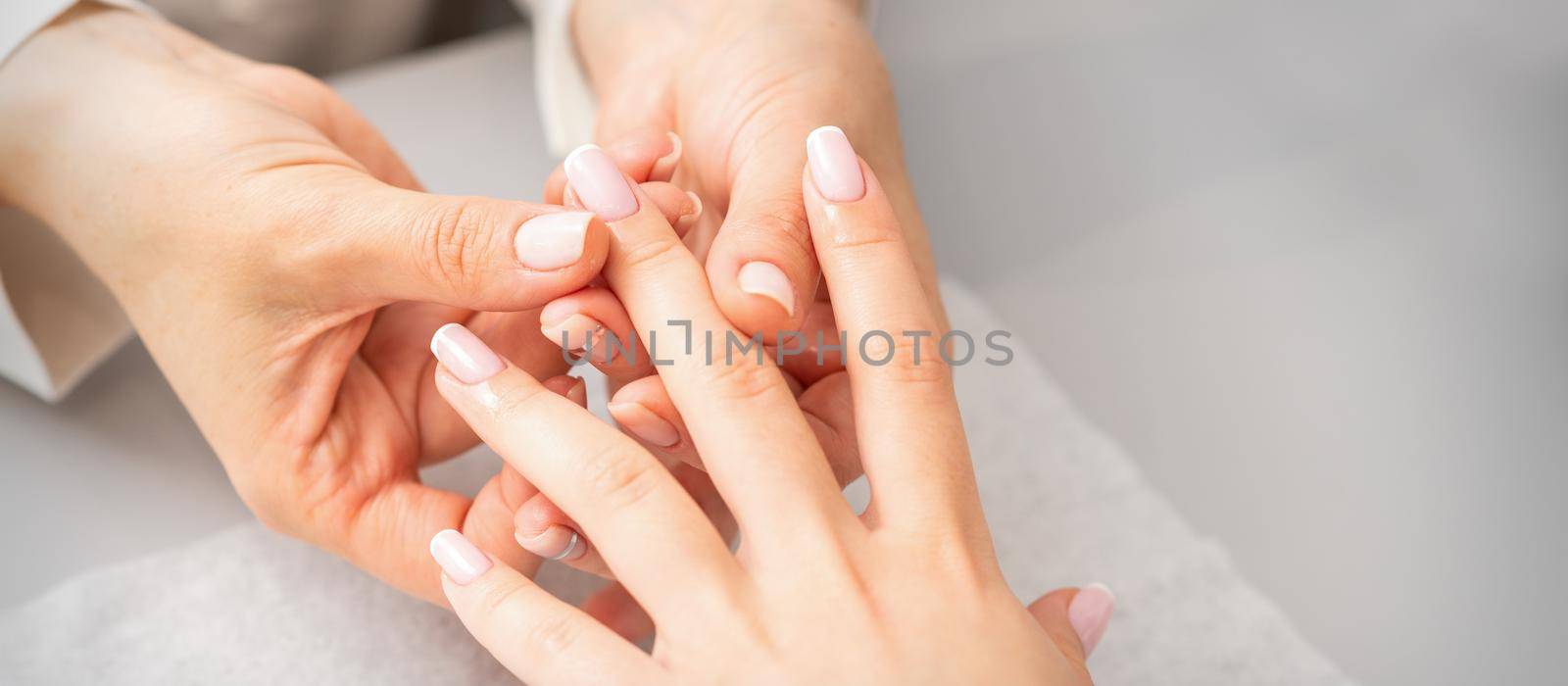 Manicure treatment at beauty spa. A hand of a woman getting a finger massage with oil in a nail salon