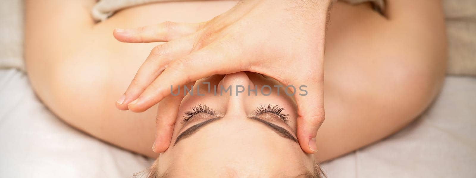 Face massage with fingers of a masseur. Female facial skin care at a beauty spa salon. by okskukuruza