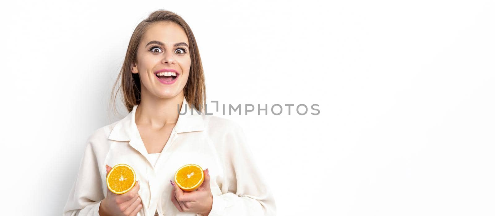 Joyful attractive young woman having two pieces of orange isolated on white background with copy space