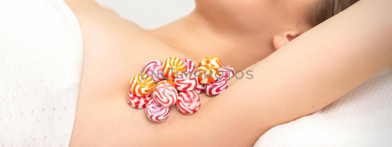 Colored round candies under the female armpit, close up, depilation armpit concept. by okskukuruza