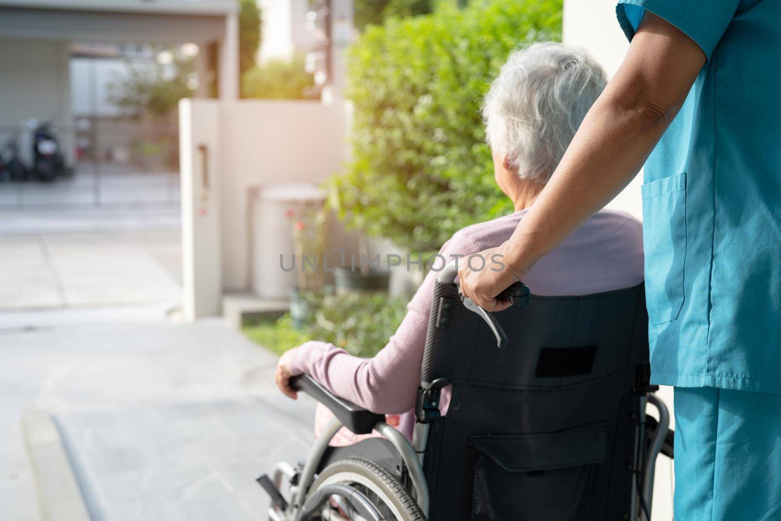 Caregiver help and care Asian senior or elderly old lady woman patient sitting in wheelchair on ramp at nursing hospital, healthy strong medical concept by pamai