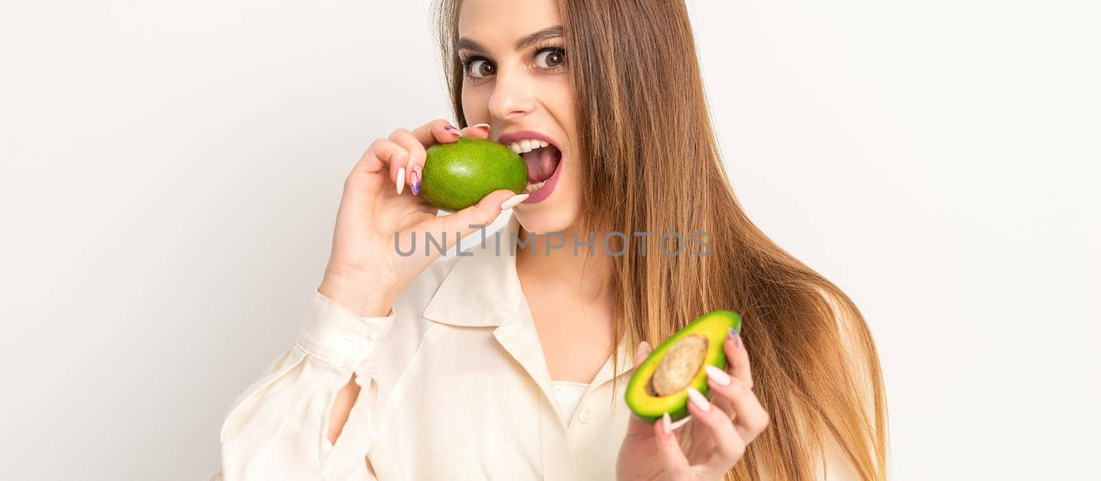 Diet nutrition. Beautiful young caucasian woman biting organic green avocado on white background. Healthy lifestyle, health concept. by okskukuruza