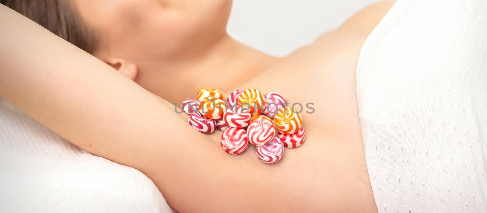 Colored round candies under the female armpit, close up, depilation armpit concept