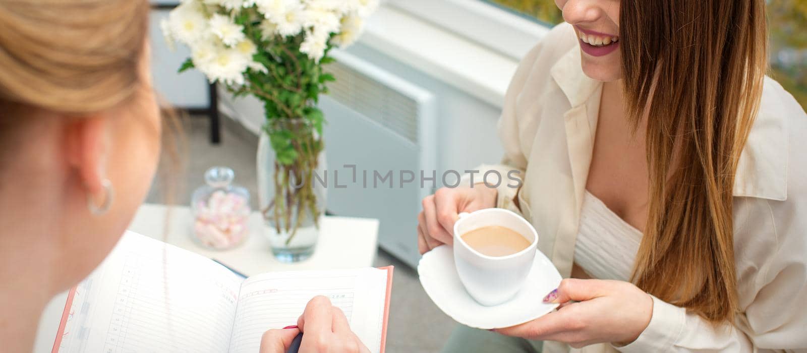 The young caucasian woman has a coffee and appointment with a female doctor in hospital office